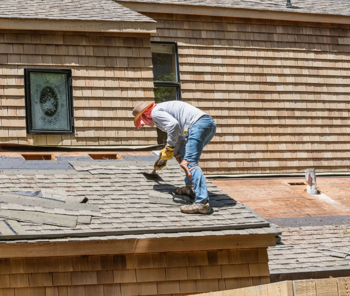 Roofer repairing shingles on a roof