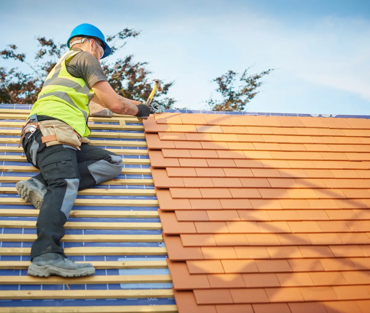 Roofer installing orange tiles on roof